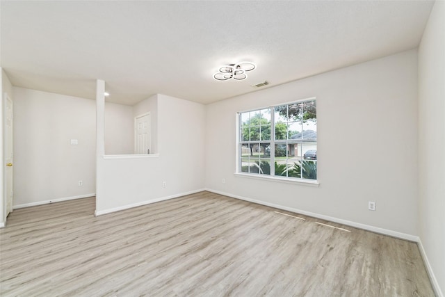 unfurnished room with baseboards, visible vents, and wood finished floors