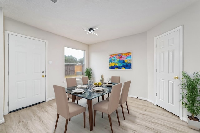 dining space with baseboards and light wood-style flooring