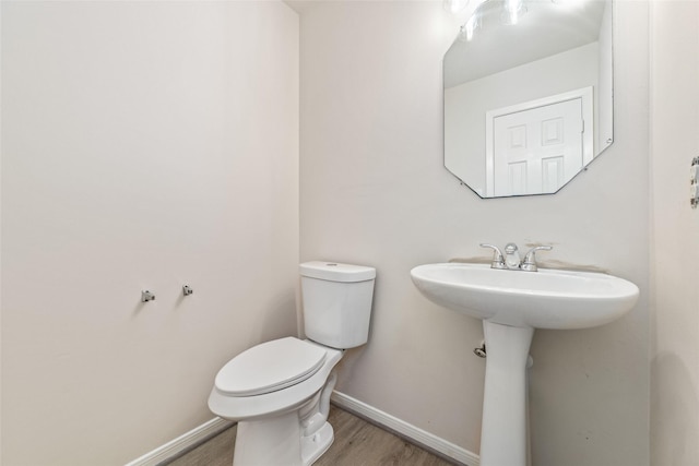 bathroom featuring baseboards, wood finished floors, and toilet
