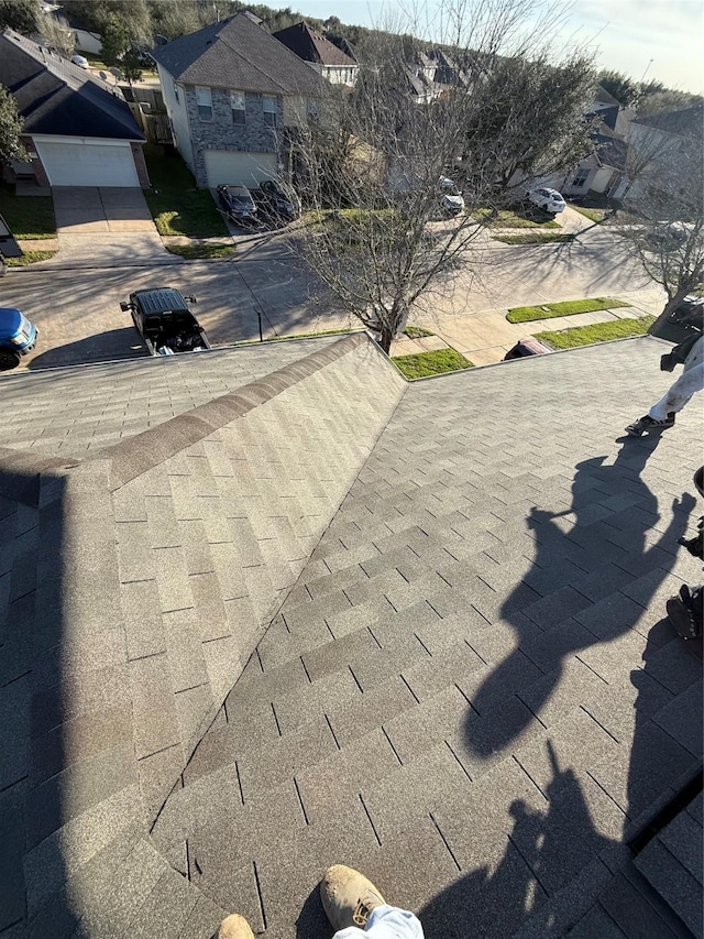 details featuring driveway, a residential view, and roof with shingles