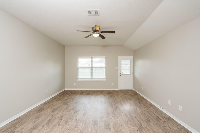 unfurnished room featuring a ceiling fan, visible vents, wood finished floors, baseboards, and lofted ceiling