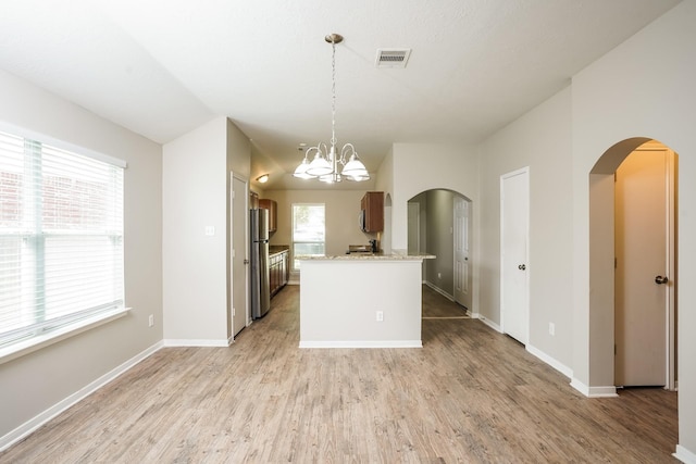 kitchen featuring arched walkways, freestanding refrigerator, light wood-style flooring, and visible vents