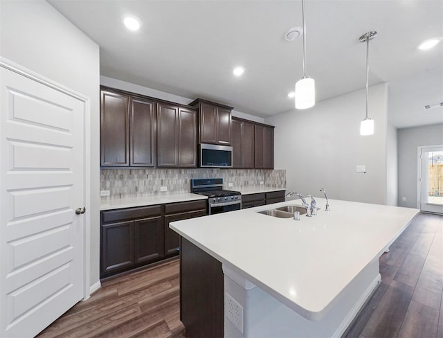 kitchen with a sink, backsplash, stainless steel appliances, and dark wood finished floors