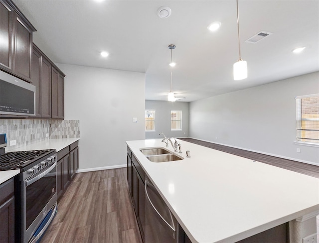kitchen featuring dark brown cabinets, appliances with stainless steel finishes, a sink, dark wood-type flooring, and visible vents