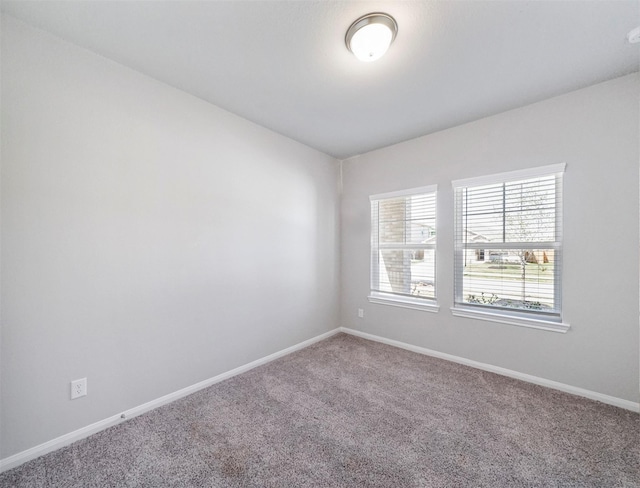 carpeted empty room featuring baseboards