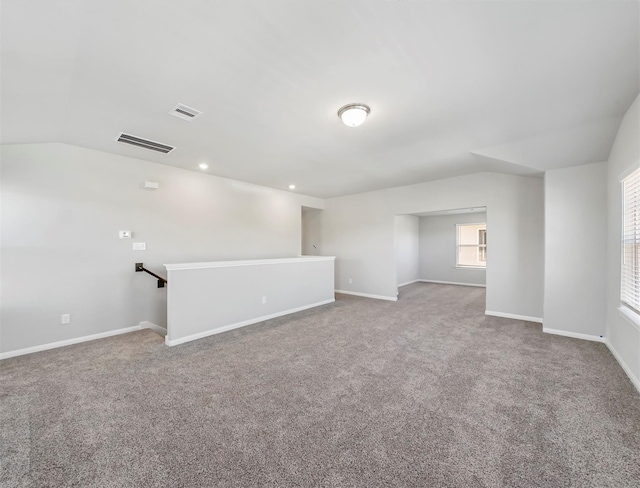 carpeted spare room with visible vents, recessed lighting, baseboards, and vaulted ceiling