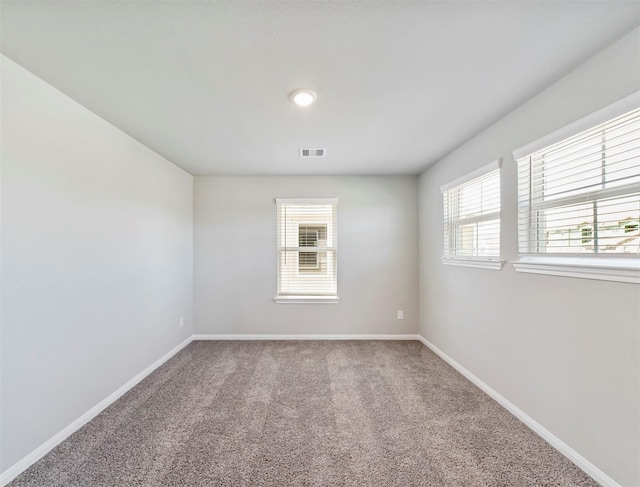 carpeted spare room featuring baseboards and visible vents