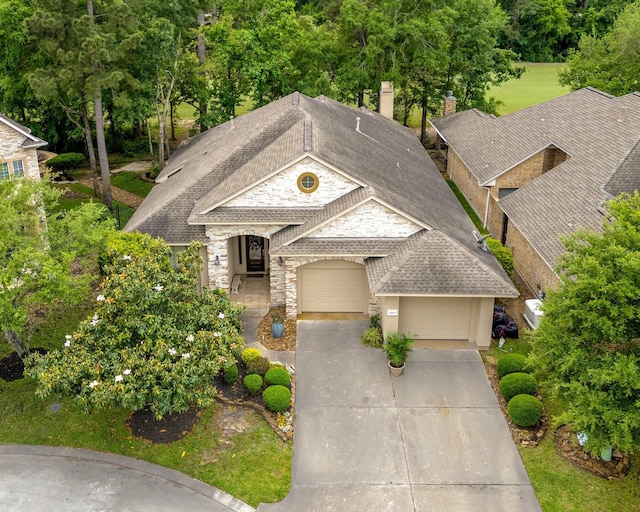 view of front of property featuring a garage, roof with shingles, stone siding, and concrete driveway