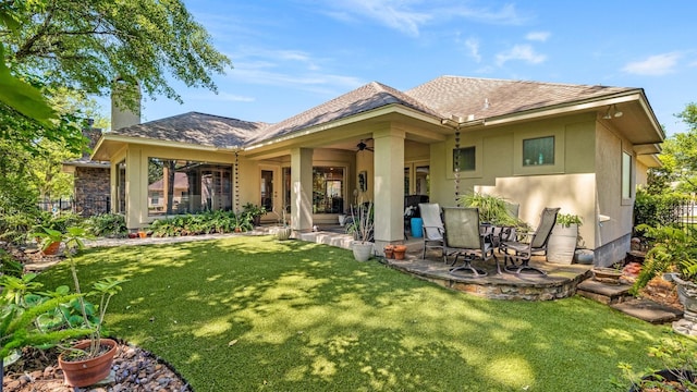rear view of house featuring fence, stucco siding, a chimney, a patio area, and a lawn