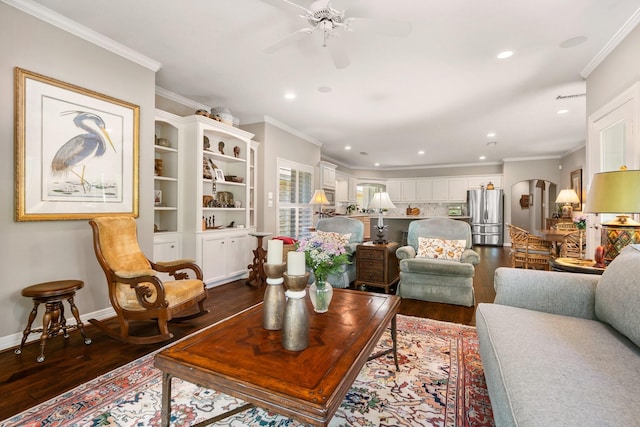 living room featuring a ceiling fan, crown molding, arched walkways, recessed lighting, and dark wood-type flooring