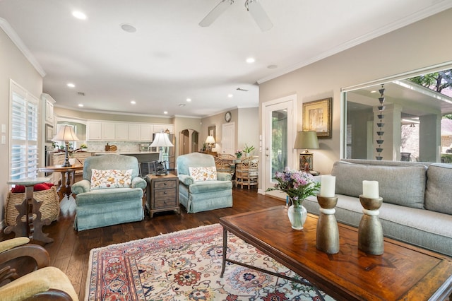 living room with ornamental molding, ceiling fan, recessed lighting, arched walkways, and dark wood finished floors
