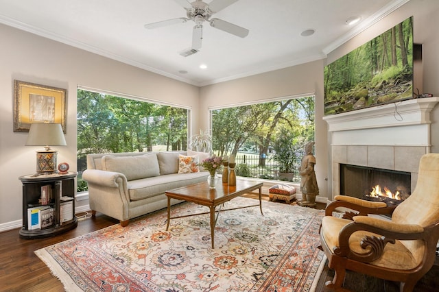 living area featuring visible vents, ornamental molding, wood finished floors, a fireplace, and a ceiling fan