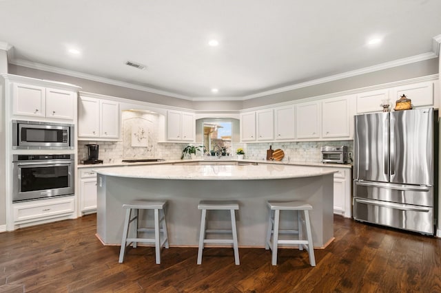 kitchen featuring appliances with stainless steel finishes, white cabinets, a kitchen island, and visible vents