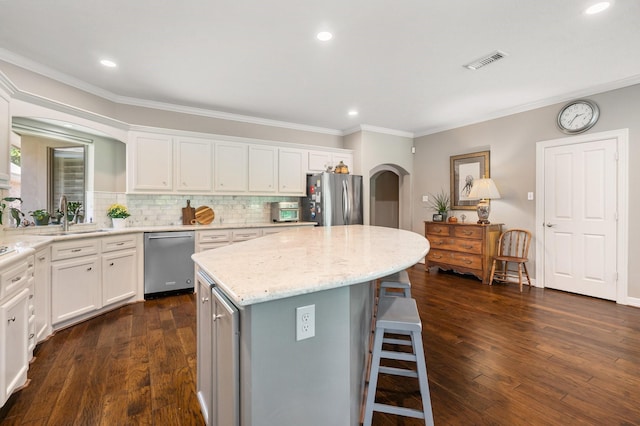 kitchen with a sink, arched walkways, stainless steel appliances, a kitchen bar, and visible vents