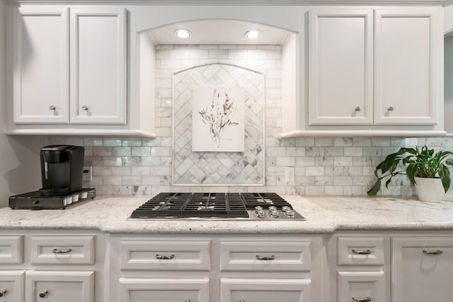 kitchen with stainless steel gas stovetop, decorative backsplash, and white cabinets