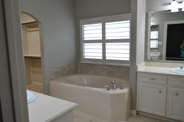bathroom featuring tile patterned floors, a spacious closet, a bath, and vanity