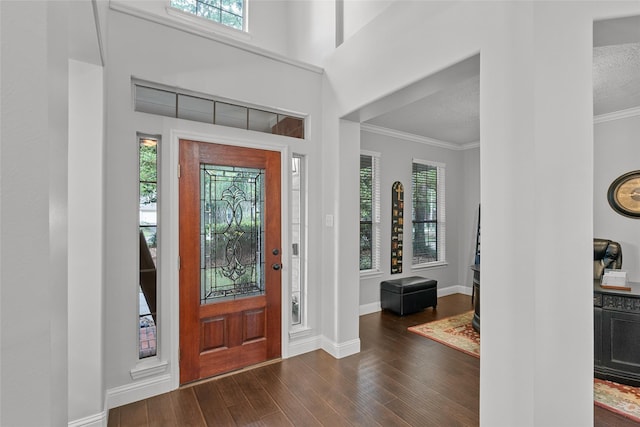 entrance foyer featuring baseboards, ornamental molding, a textured ceiling, and wood finished floors