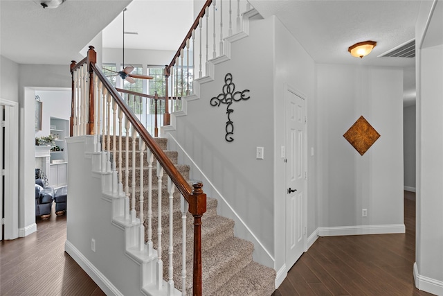 staircase with baseboards, a ceiling fan, wood finished floors, and visible vents