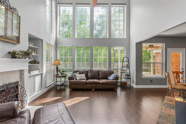 living room featuring plenty of natural light, a high ceiling, a fireplace, and wood finished floors