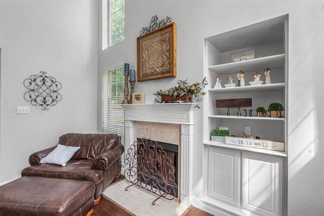 sitting room with built in features, a fireplace, and wood finished floors