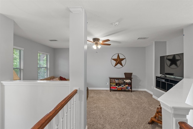 interior space with carpet floors, visible vents, baseboards, and an upstairs landing