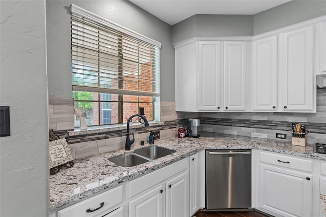 kitchen featuring stainless steel dishwasher, a sink, backsplash, and white cabinets