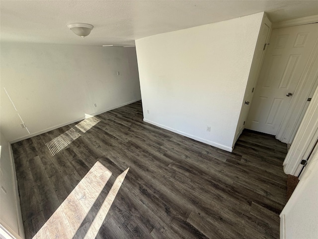 unfurnished room featuring baseboards and dark wood-style flooring