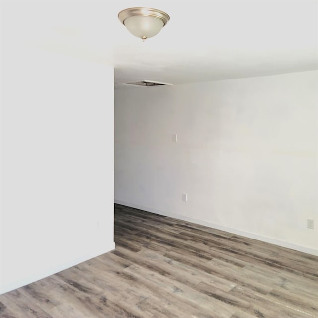 unfurnished room with baseboards and wood finished floors