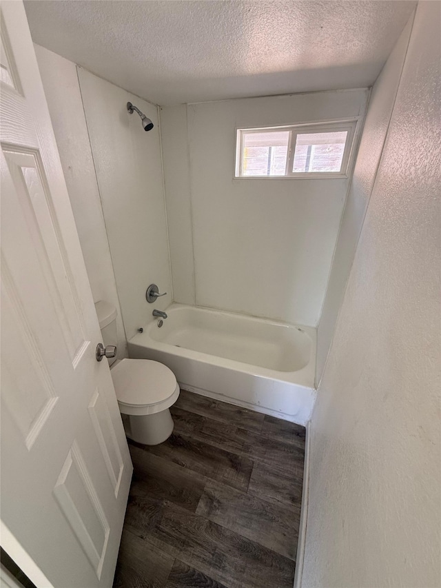 full bath featuring tub / shower combination, toilet, a textured ceiling, and wood finished floors