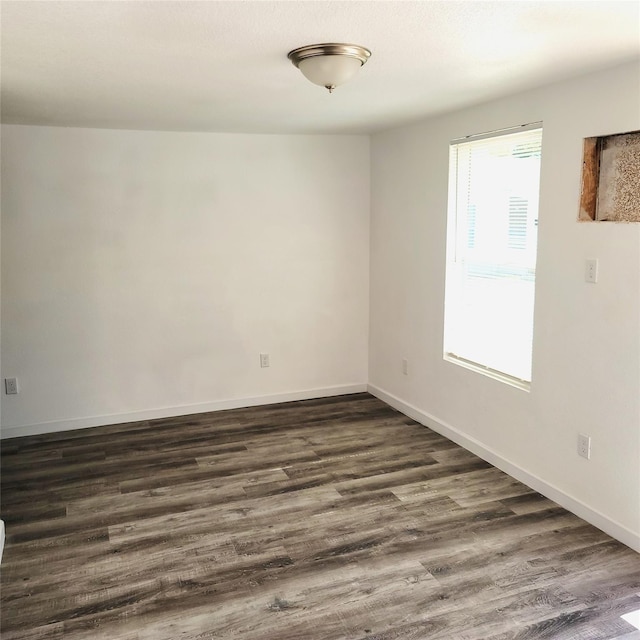 empty room featuring baseboards and dark wood-style flooring