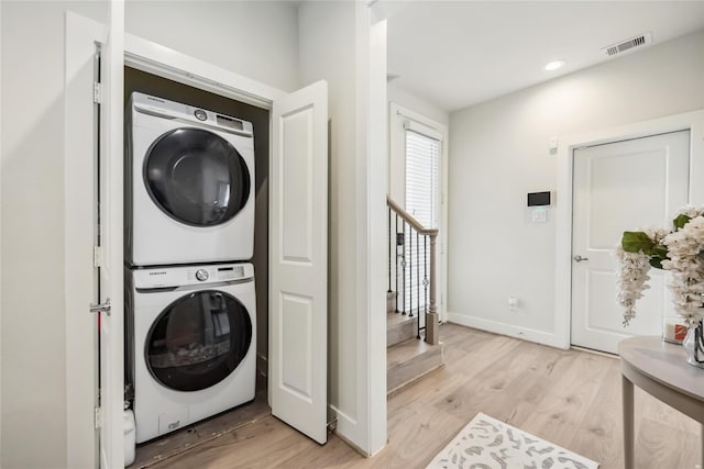 clothes washing area featuring laundry area, stacked washer and dryer, light wood-style flooring, and visible vents