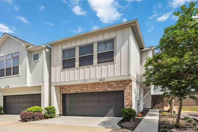 multi unit property with board and batten siding, brick siding, driveway, and a garage