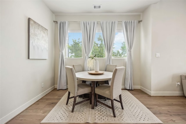 dining room featuring baseboards, visible vents, and light wood finished floors