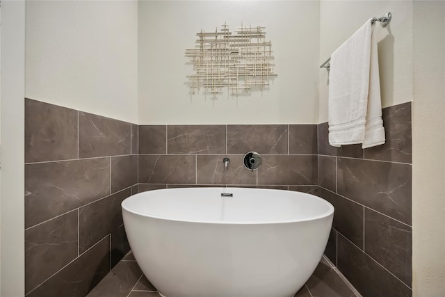 full bath featuring a freestanding tub, tile walls, and wainscoting