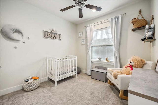 bedroom featuring baseboards, carpet flooring, a crib, and ceiling fan