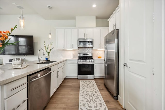 kitchen with backsplash, white cabinets, appliances with stainless steel finishes, and a sink