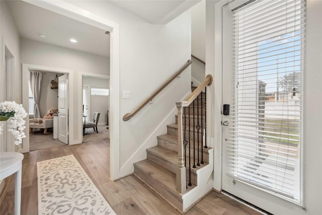 stairs featuring recessed lighting, a healthy amount of sunlight, and wood finished floors