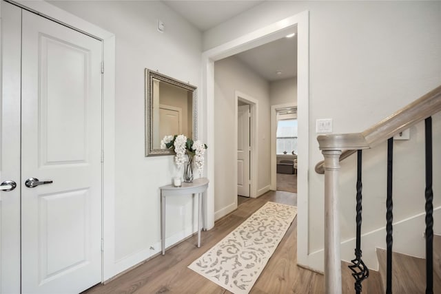 corridor featuring stairs, baseboards, and wood finished floors
