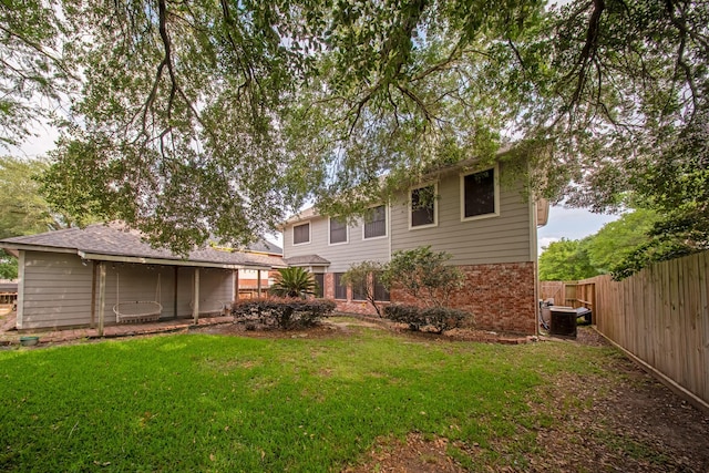 back of house with a lawn, fence, and brick siding