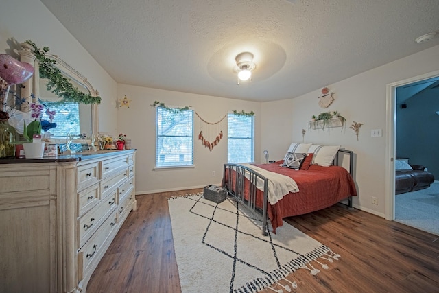 bedroom with baseboards, a textured ceiling, and dark wood-style floors