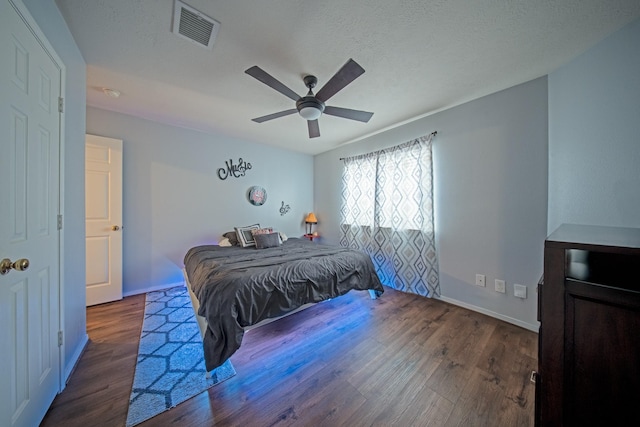 bedroom featuring baseboards, ceiling fan, visible vents, and wood finished floors