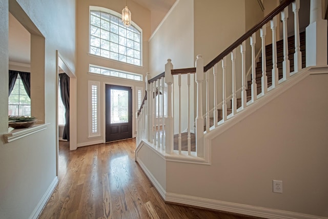 foyer with stairs, a high ceiling, baseboards, and wood finished floors