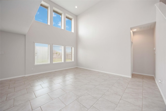unfurnished living room featuring visible vents, a towering ceiling, baseboards, recessed lighting, and light tile patterned flooring