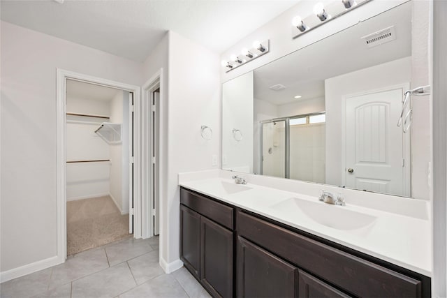 bathroom featuring a sink, a walk in closet, a shower stall, and visible vents