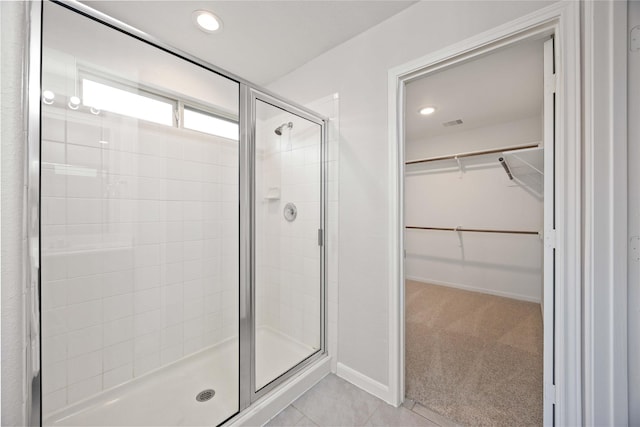 bathroom featuring baseboards, recessed lighting, a walk in closet, and a shower stall