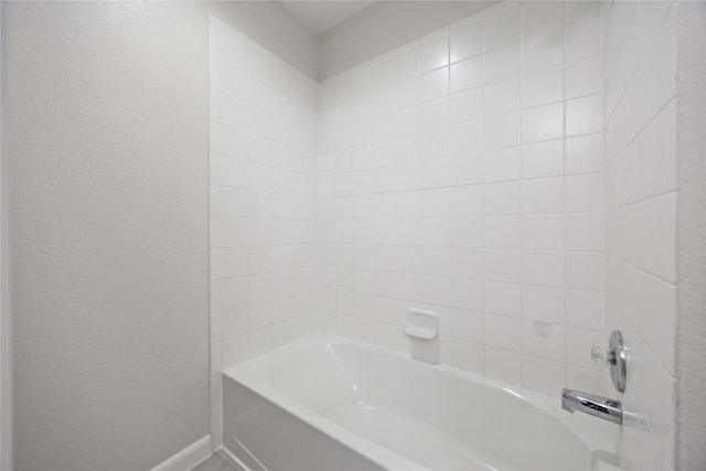 full bath with shower / bath combination, baseboards, and a textured wall