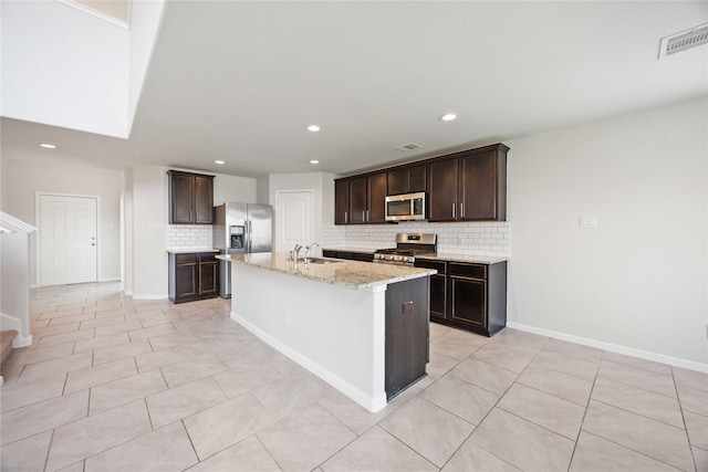 kitchen with a sink, appliances with stainless steel finishes, dark brown cabinetry, and backsplash