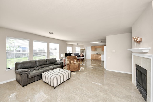living room with baseboards, visible vents, and a tile fireplace