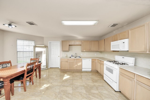 kitchen featuring visible vents, light countertops, a sink, light brown cabinets, and white appliances