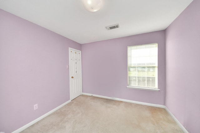 empty room with visible vents, baseboards, and light colored carpet